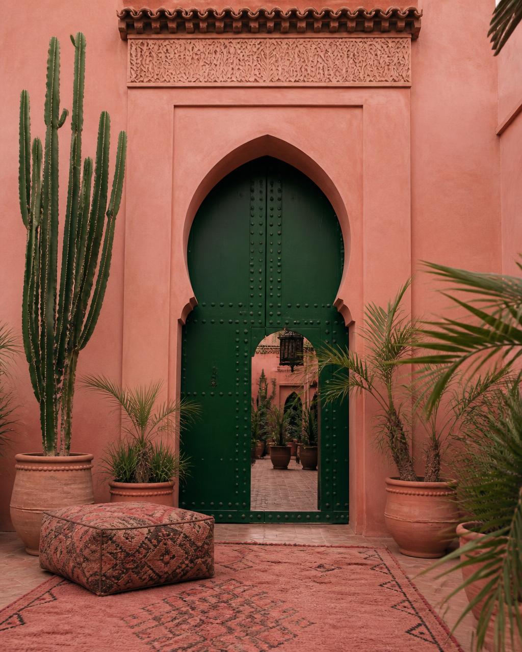 Porte en bois d'un riad à Marrakech encadrée de cactus et de poteries en terracotta